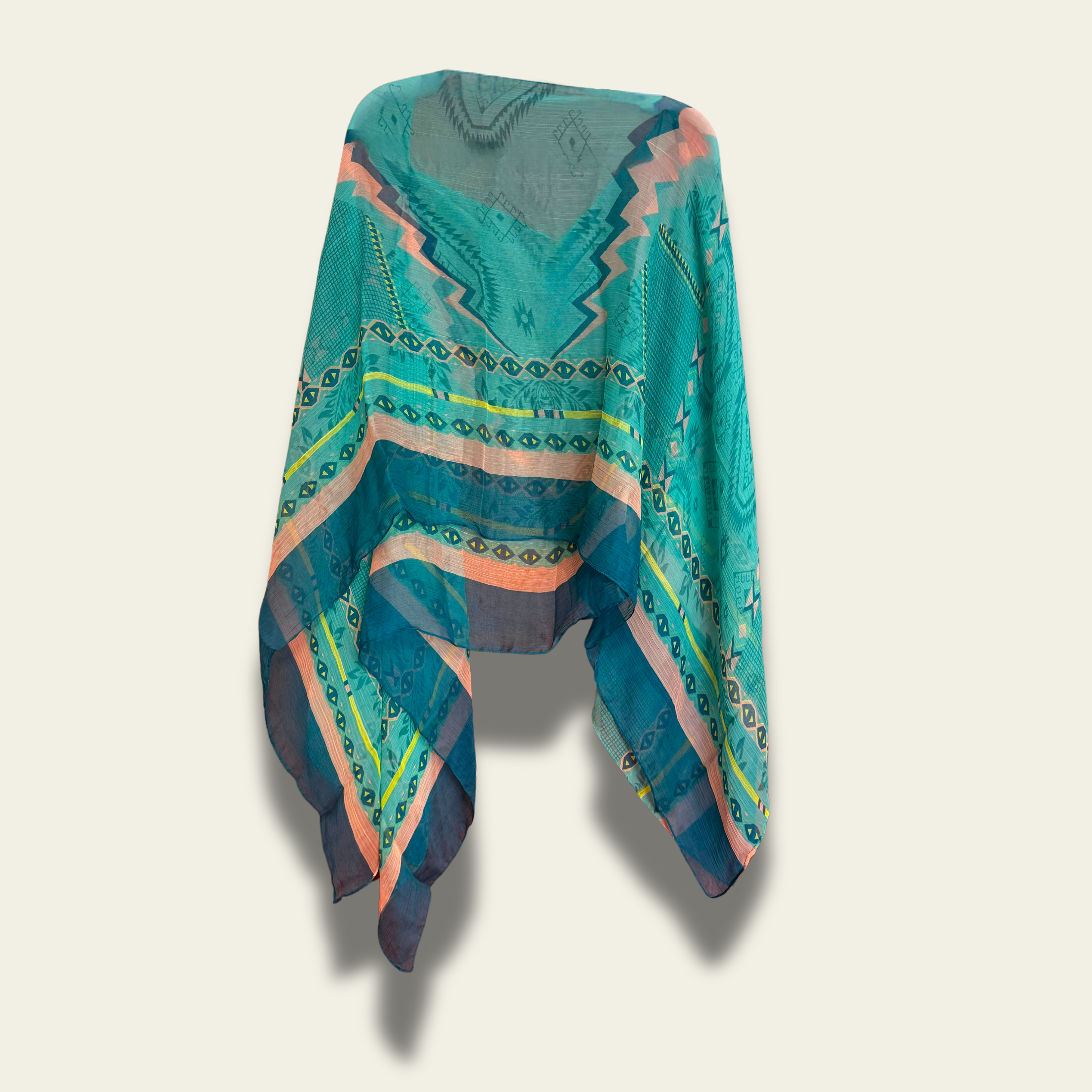 This lightweight chiffon poncho drapes beautifully, showcasing a vibrant blend of turquoise and coral with an abstract print.